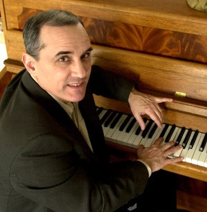 Dan Barker sitting at a piano