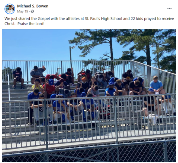 High school athletes praying while sitting in the bleachers outdoors