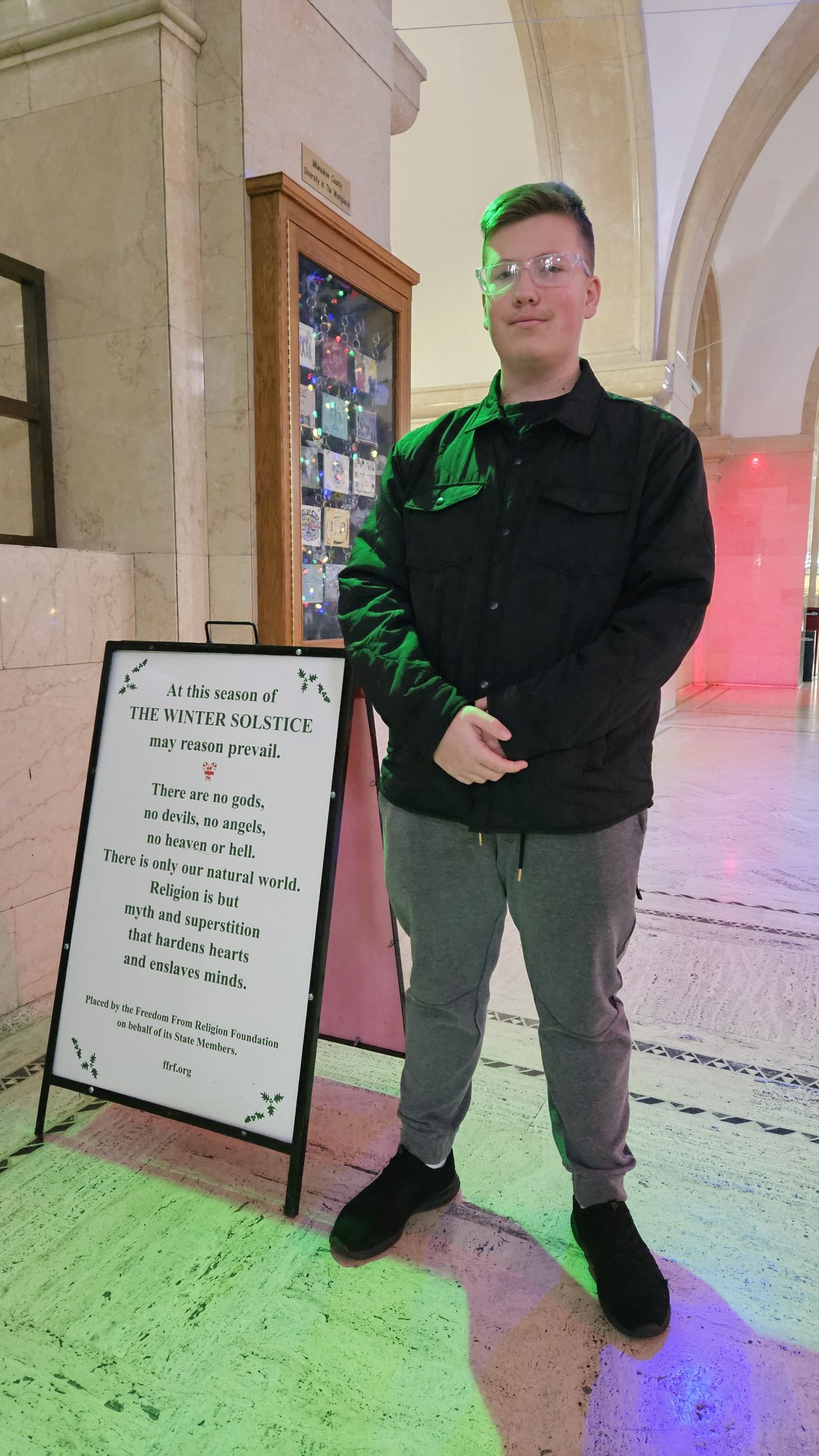 FFRF employee standing next to the FFRF Solstice message at the Milwaukee County Courthouse