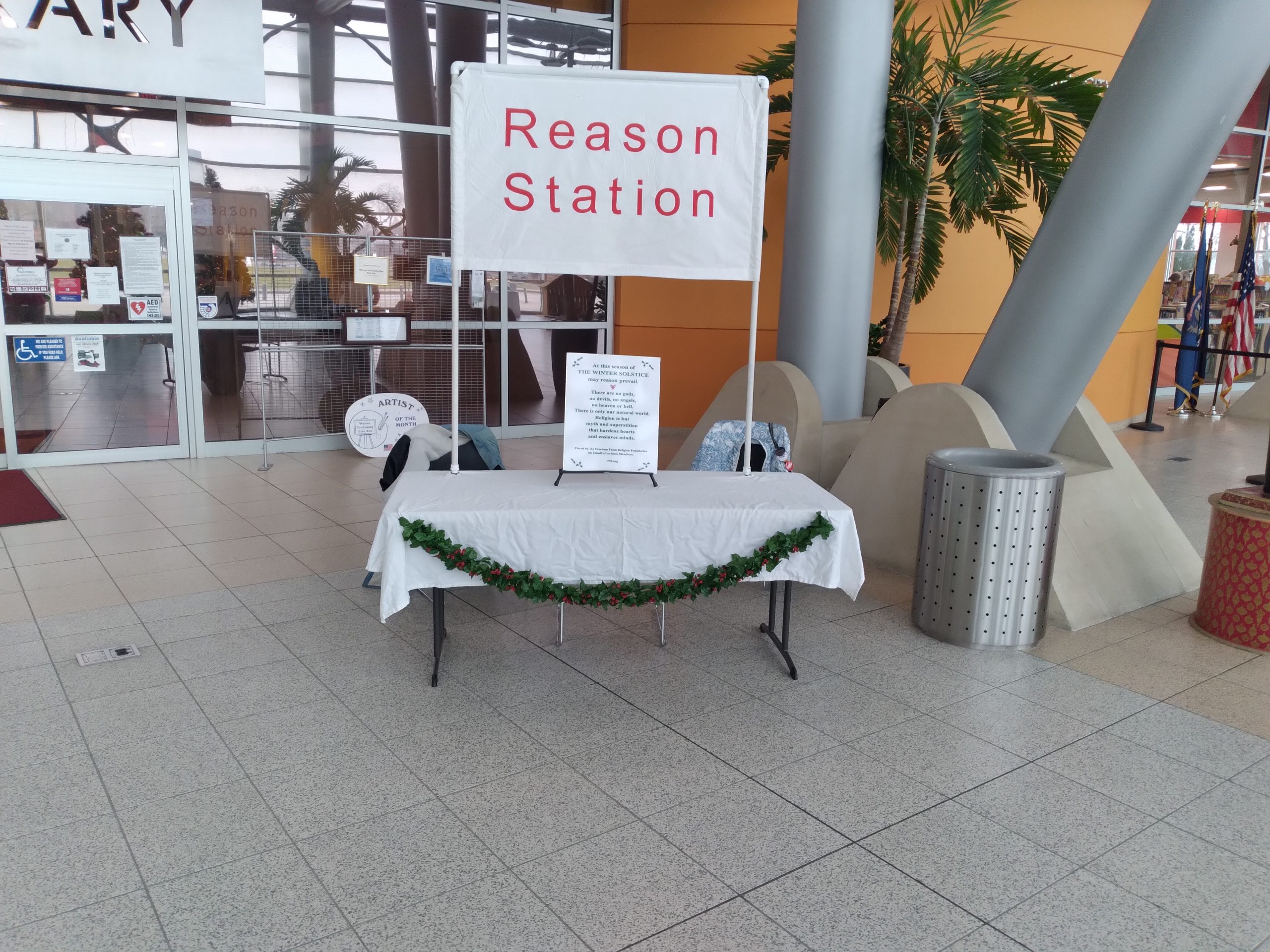 A table outside a building with a banner above it reading "Reason Station"