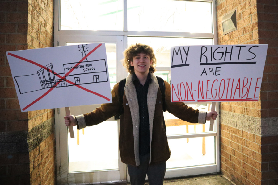 A student at Hungtington High School in West Virginia holds two protest signs, one of which says "My Rights aree Non-negotiable"