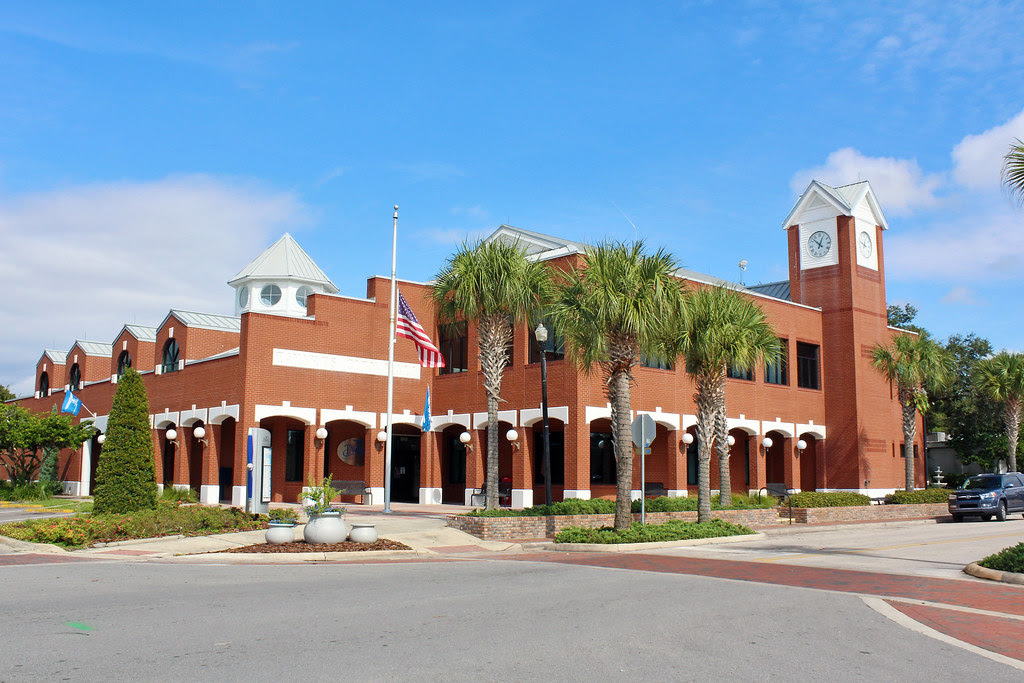 outdoor shot of a Florida city council building made of brick with a clock tower and a clear blue sky behind it
