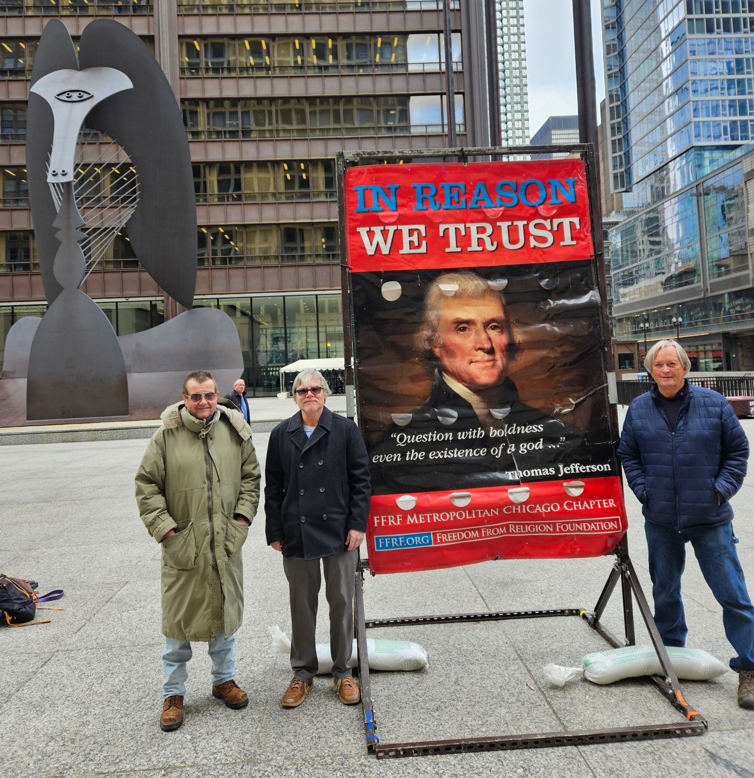 A group of men in front of a sign reading "In Reason We Trust" in Chicago