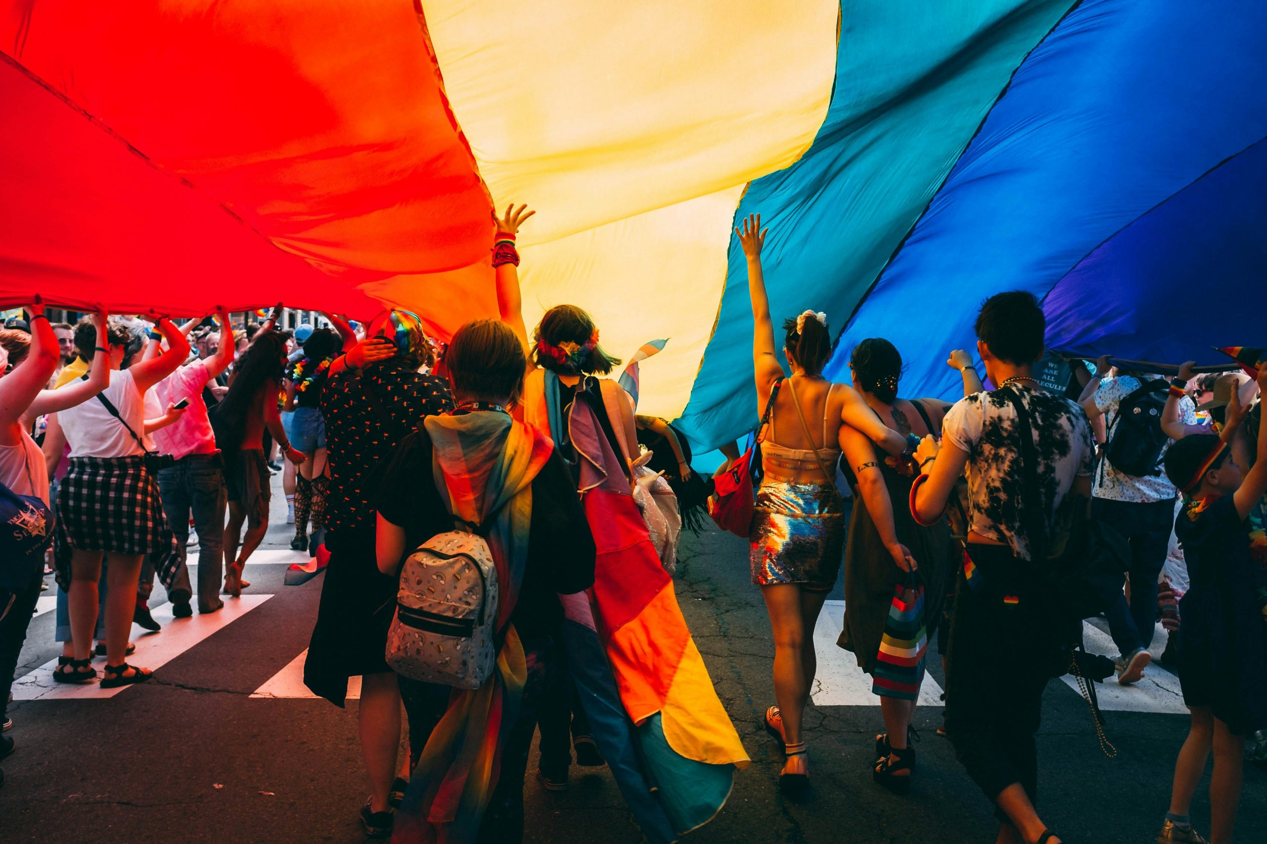 A group of students underneath a giant pride flag