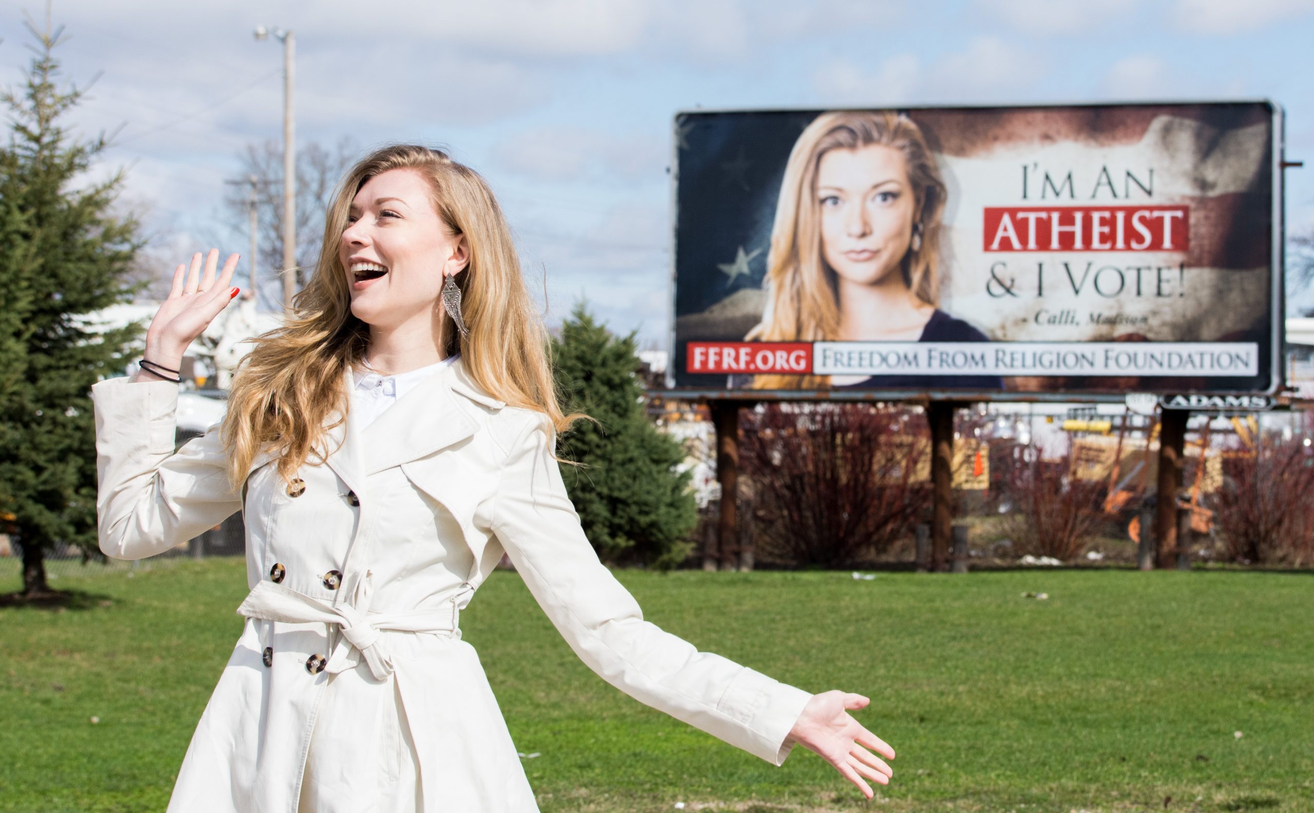 woman in trench coat standing in front of a billboard